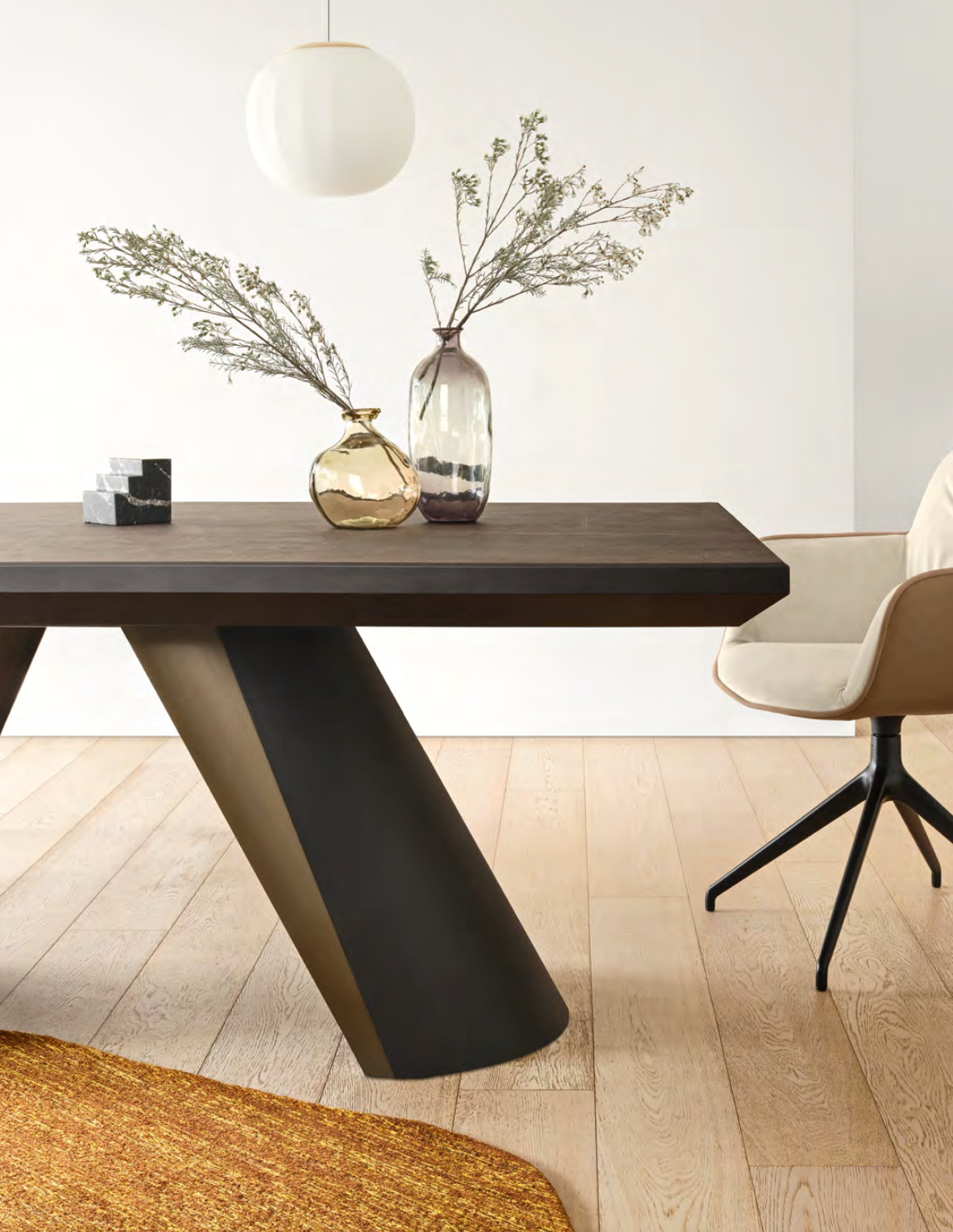 A modern dining room with minimalist decor featuring neutral-toned furniture, including a beige chair, dark wood table, and decorative glass vases with dried branches, highlighting trending furniture colors for 2025.