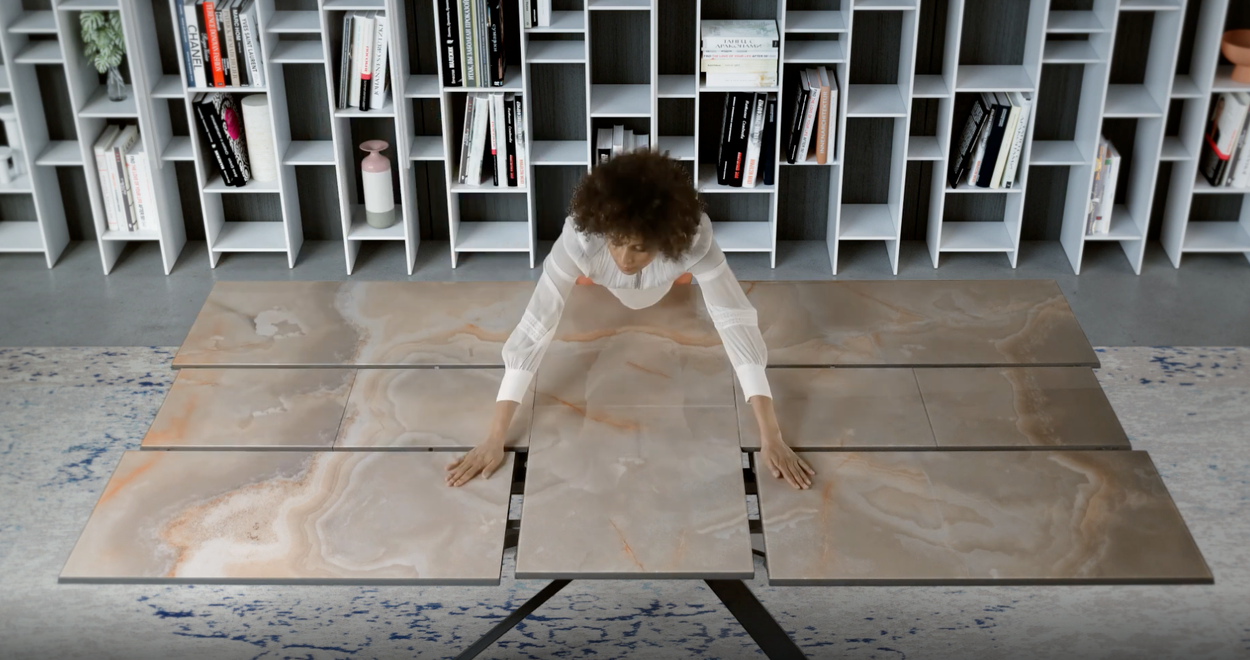 A person demonstrating the transformable marble dining table of Ozzio Italia, showcasing its sleek, modular design for versatile living spaces.