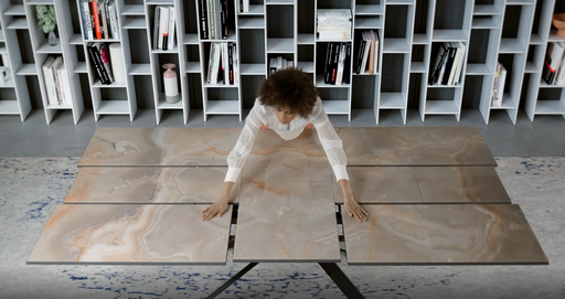 A person demonstrating the transformable marble dining table of Ozzio Italia, showcasing its sleek, modular design for versatile living spaces.