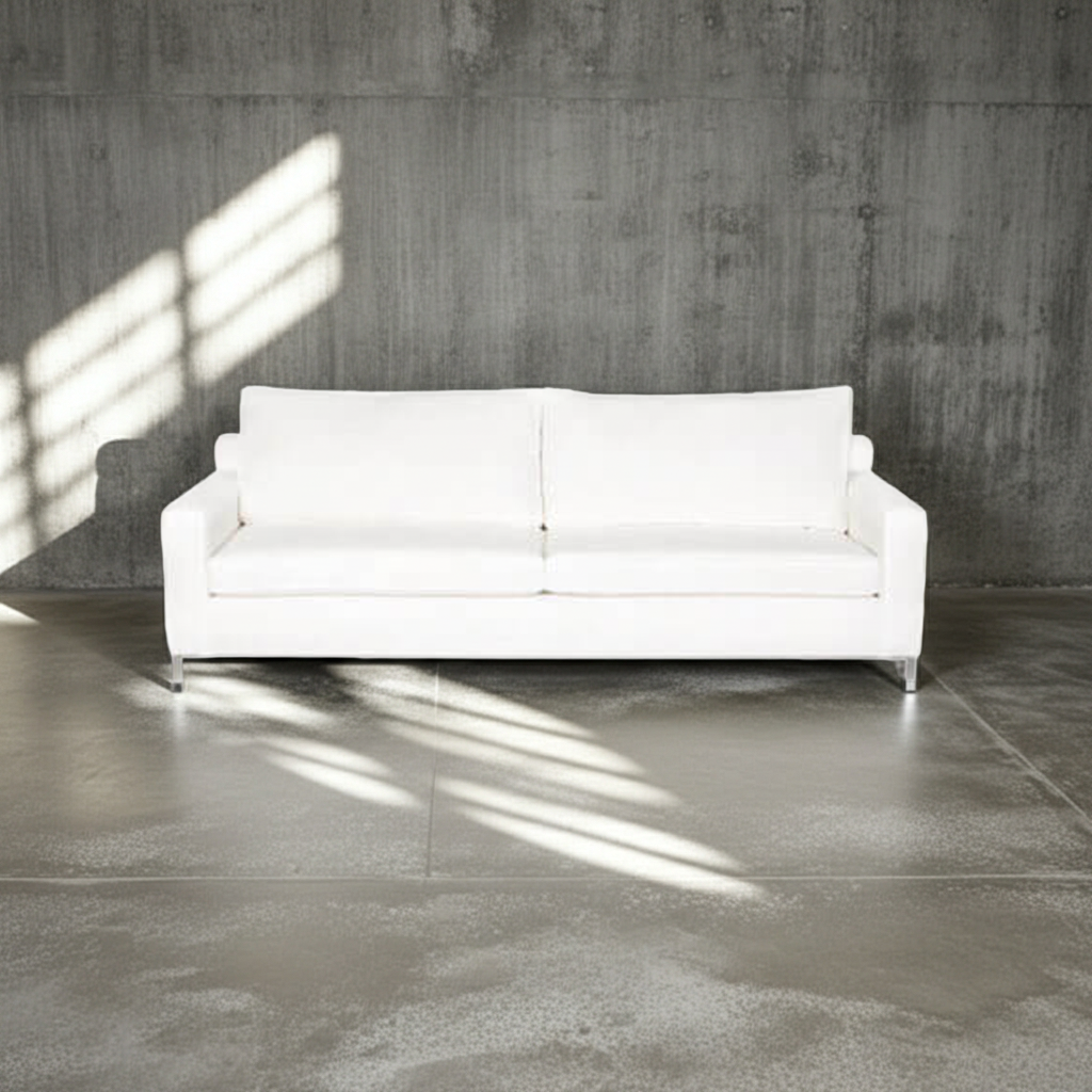 White sofa in a room with concrete walls and floor
