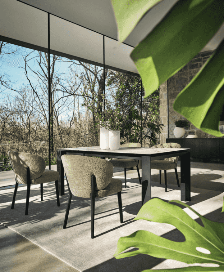 Set of CS2243 Mara Dining Chairs by Calligaris with dark wood legs around a black dining table in a glass-walled room with natural light.