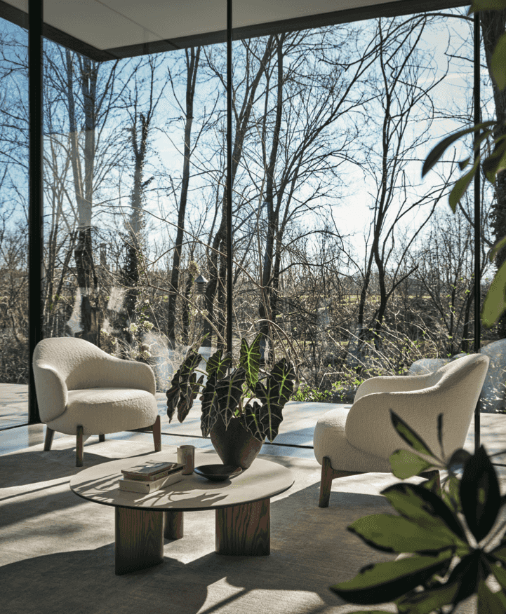 Pair of CS3463 Holly Fab Lounge Chairs by Calligaris in boucle fabric, arranged in a sunlit room with floor-to-ceiling windows and forest view.