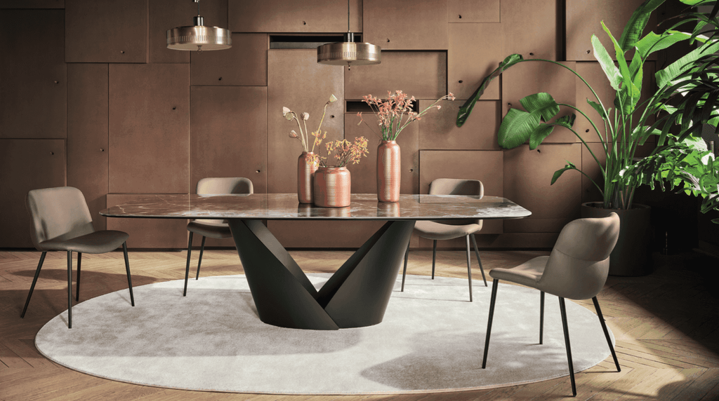 Contemporary round dining table with a marble top and a sculptural black base, surrounded by beige upholstered chairs in a stylish dining room.