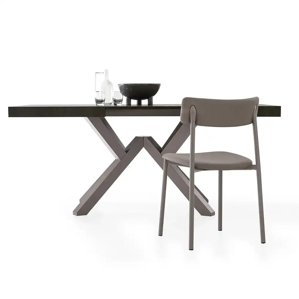 Close-up of a dark stone dining table with a matte finish, decorated with glassware and a black bowl, in a minimalist setting