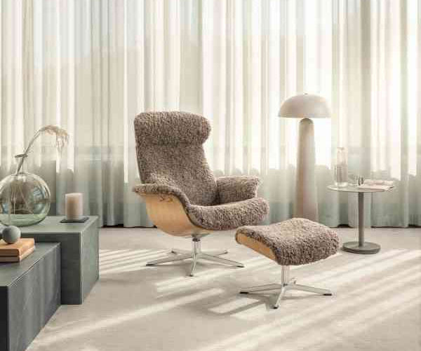 Large recliner lounge chair with plush textured fabric, matching footstool, in a bright room with sheer curtains and modern decor