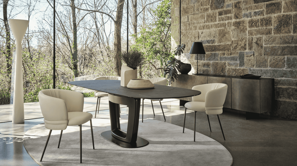 CS2238 Vanilla Dining Chairs with Wood Legs by Calligaris.com arranged around a modern table in a sunlit room with stone walls and large windows.