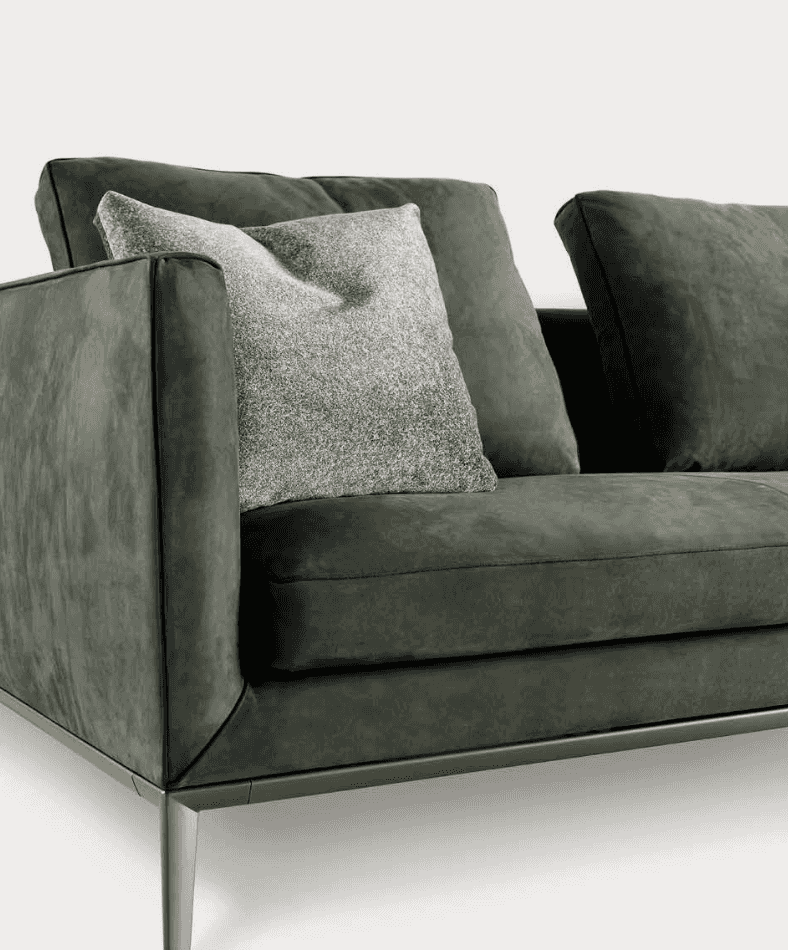Dark green velvet sofa with sleek metal legs and a textured gray throw pillow, modern furniture for living room decor