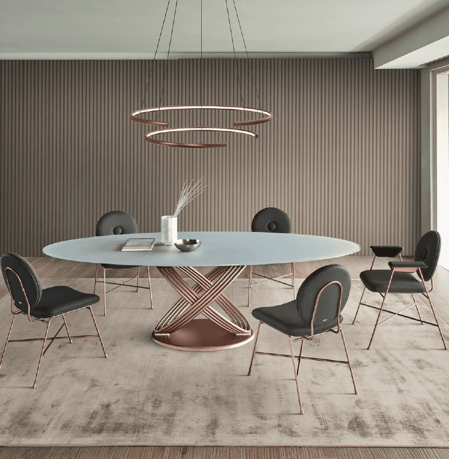 Contemporary dining space with oval table, black and rose gold chairs, circular pendant light, and textured wall panels