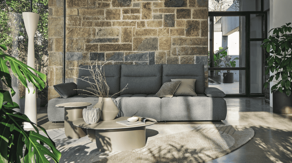 CS3467 Equipe Sofa by Calligaris in a sunlit room with stone wall backdrop, showcasing its elegant Italian craftsmanship.