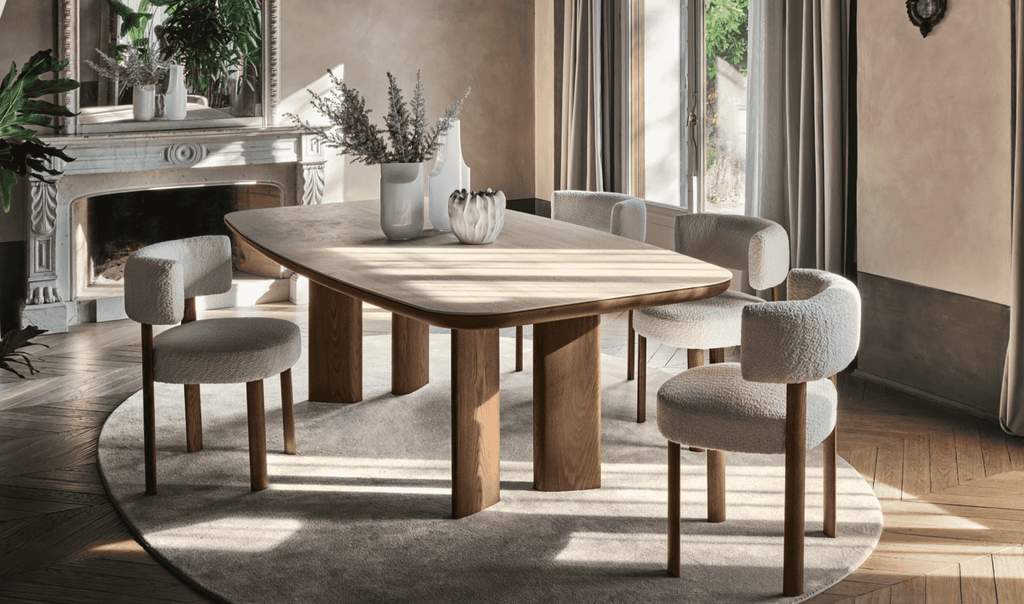 Elegant dining area featuring a wooden table with rounded edges, beige upholstered Glen chairs with wooden legs, and a classic fireplace