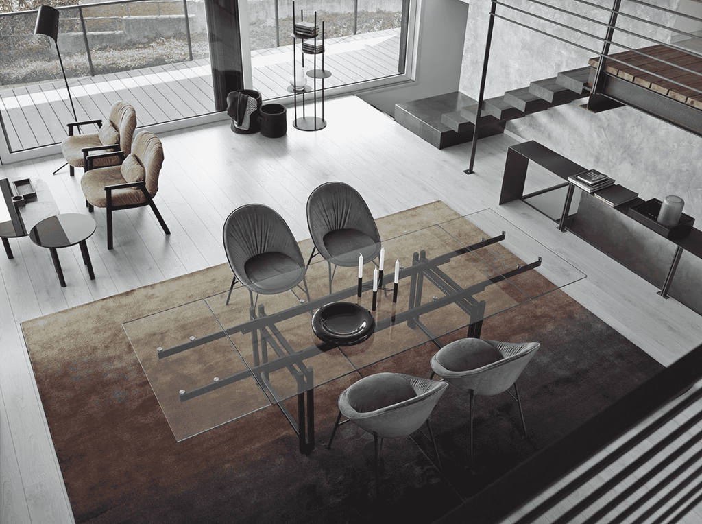 CS7192 Sky Rug by Calligaris in a dining room with glass table and grey chairs, adding warmth and contrast to modern decor.