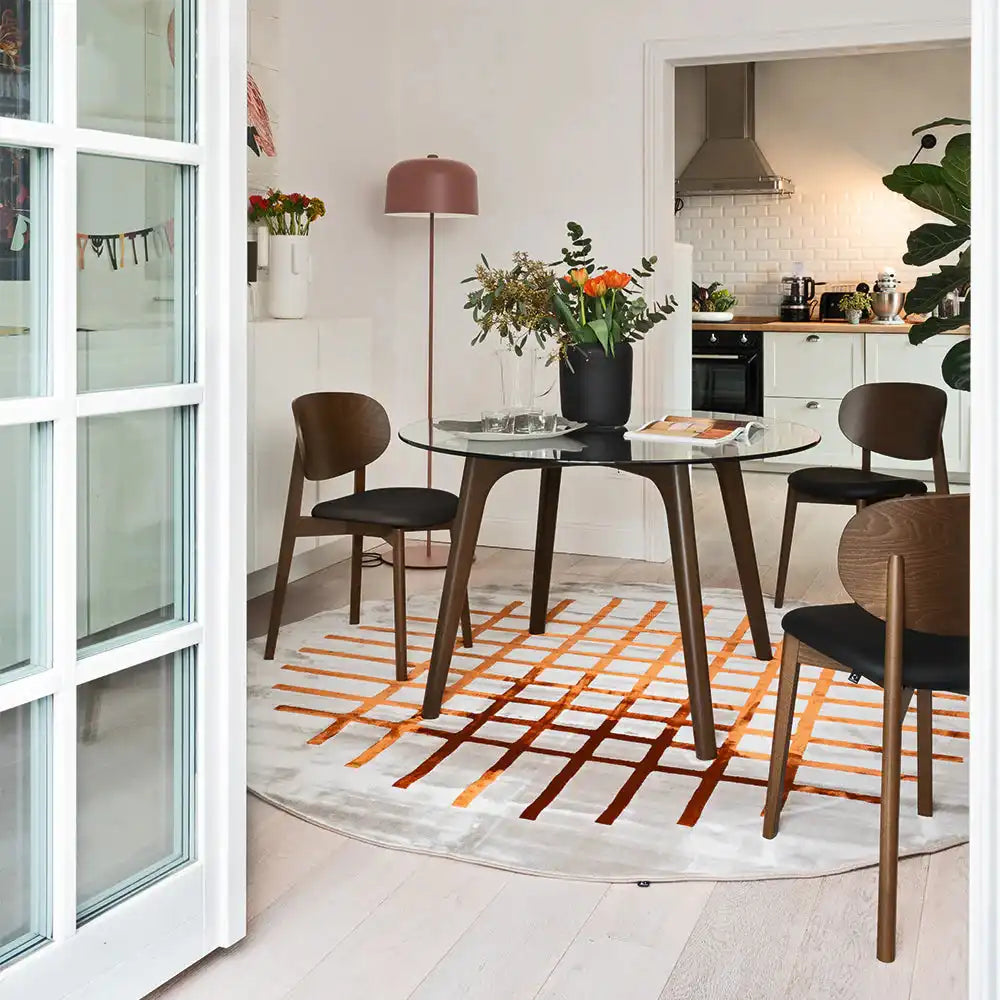 Contemporary dining area featuring a round glass table with wooden legs, surrounded by matching wooden chairs with black cushions