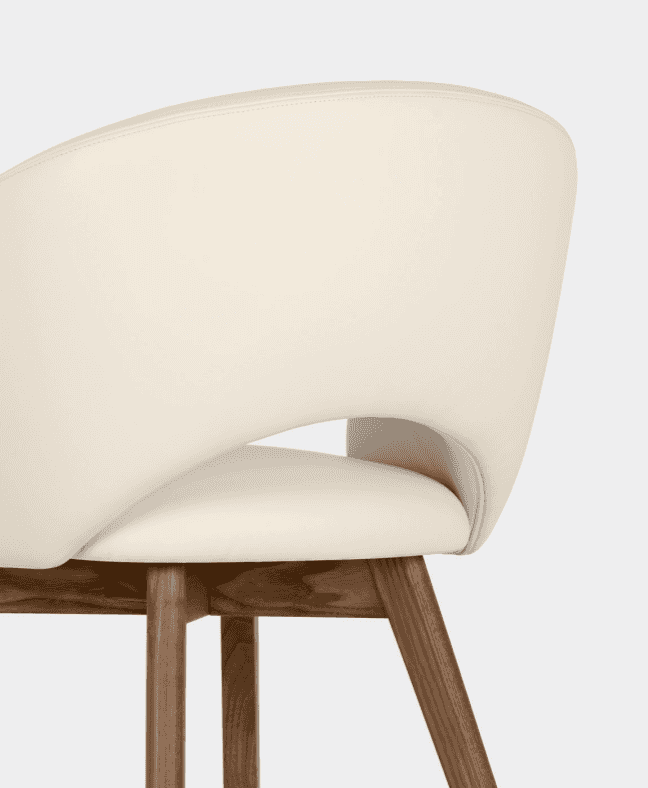 Close-up of an elegant dining chair with cream-colored leather upholstery and wooden legs, showcasing modern design and comfort.