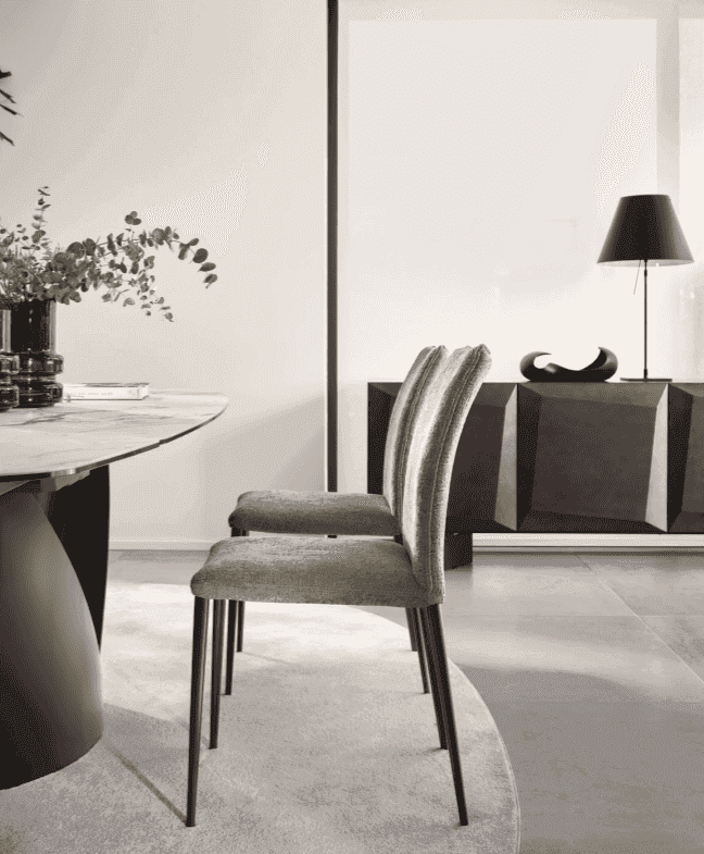 Set of two upholstered dining chairs with high backs and slender metal legs, placed in a modern dining room with natural light.