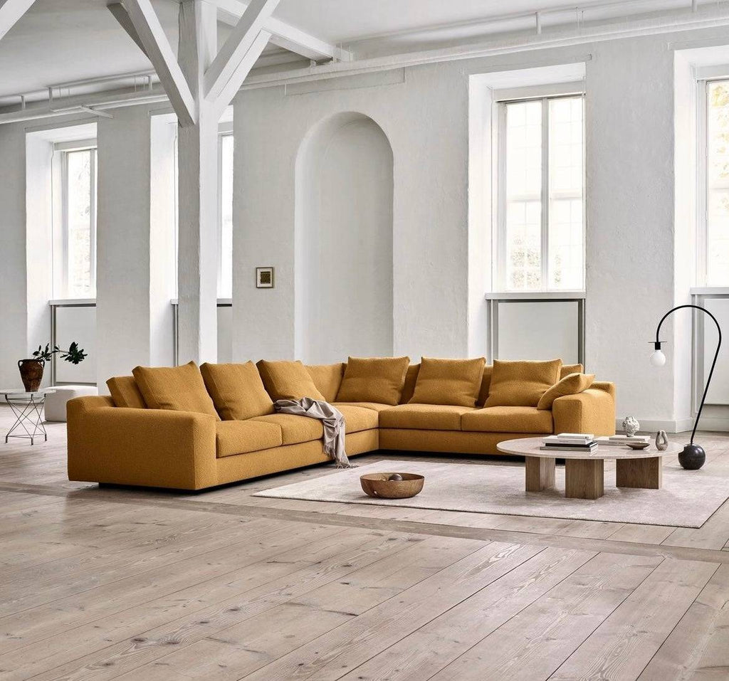Modular Aton Sofa by Eilersen in L-shaped mustard yellow configuration, featured in a spacious loft setting at Trade Source Furniture.