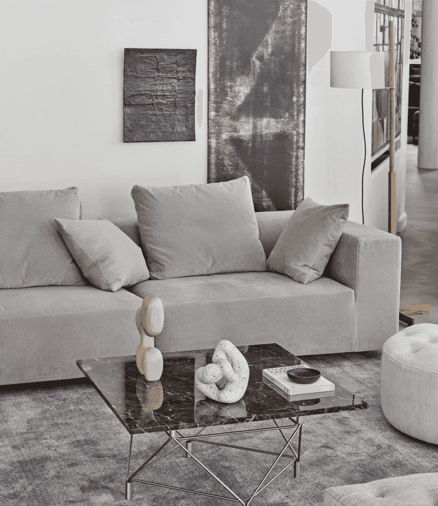 Eilersen Baseline Sofa with Chaise in neutral grey, featured in a contemporary interior with dark marble coffee table and abstract wall art.