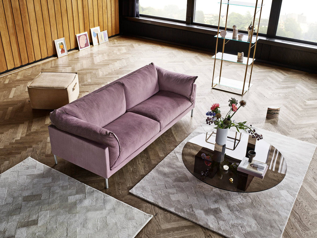 Top view of Butterfly Sofa by Eilersen in lavender fabric, styled with modern coffee tables and rugs in a bright, wood-accented living space.