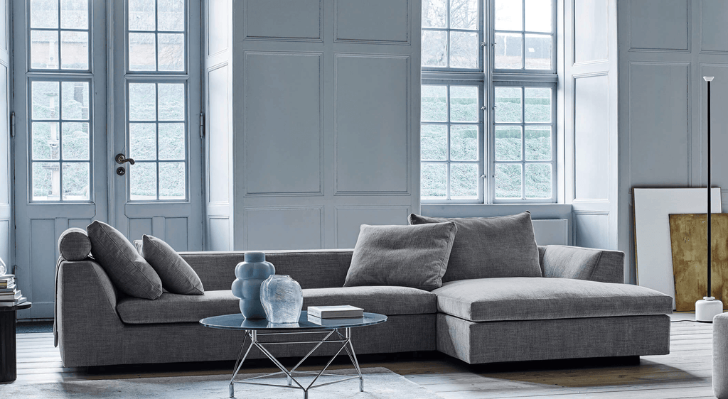 Chess Sofa by Eilersen in deep blue fabric with multiple cushions, styled in a modern interior with geometric and metallic decor.