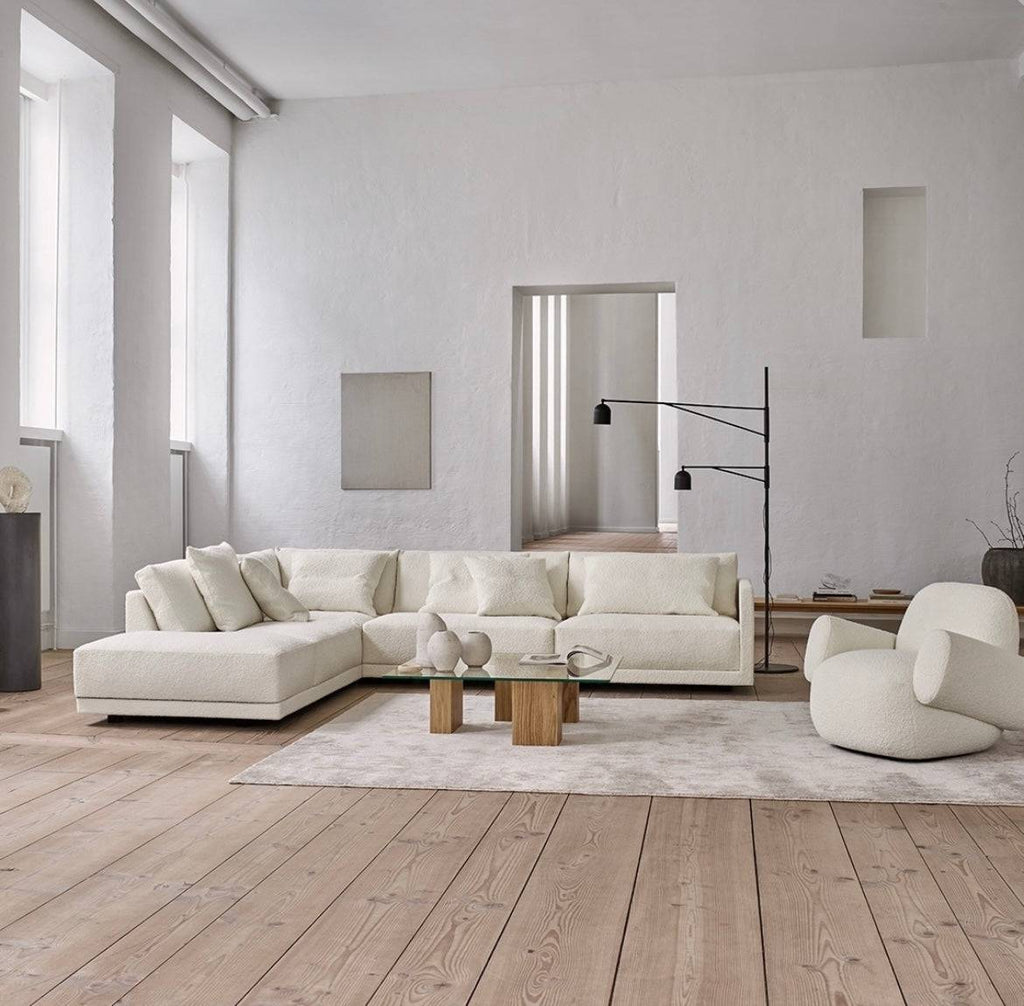 Modern living room with white sectional sofa, wooden coffee table, and minimalist decor, bright natural light, and light wood flooring