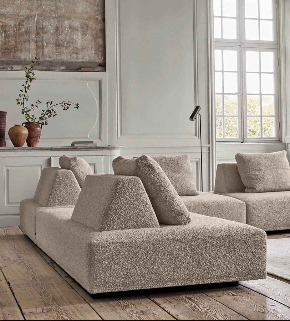 Double sided Eilersen Playground Sofa in beige boucle fabric, placed in a classic European interior with tall windows and wood floors.