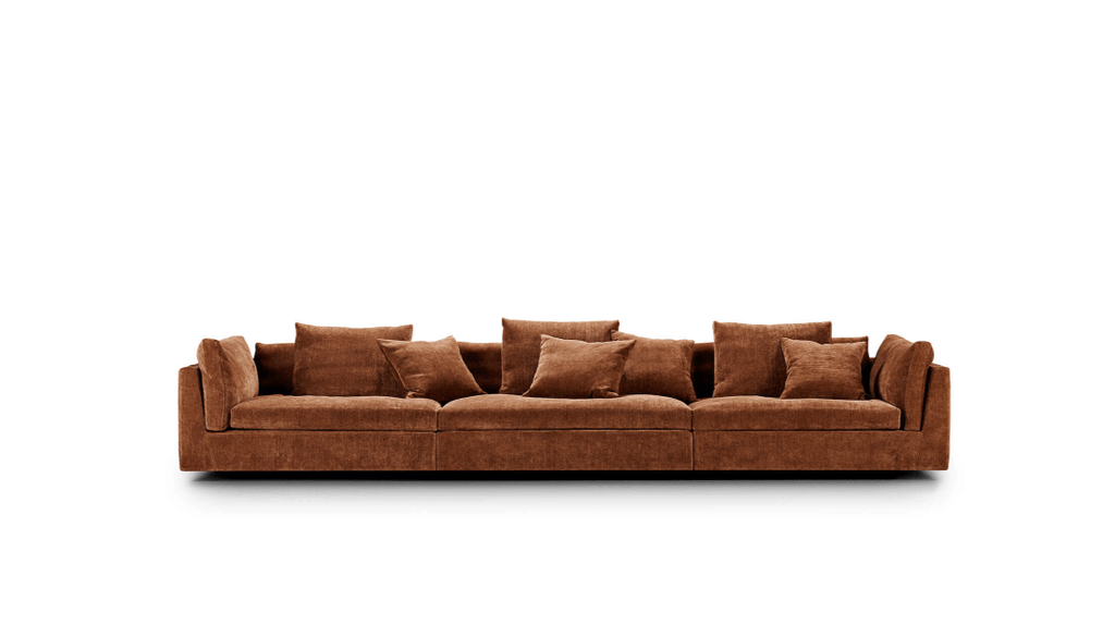 Extra-long Float Sofa by Eilersen in rust-colored fabric with multiple cushions. Ideal for spacious living rooms, available at Trade Source Furniture.