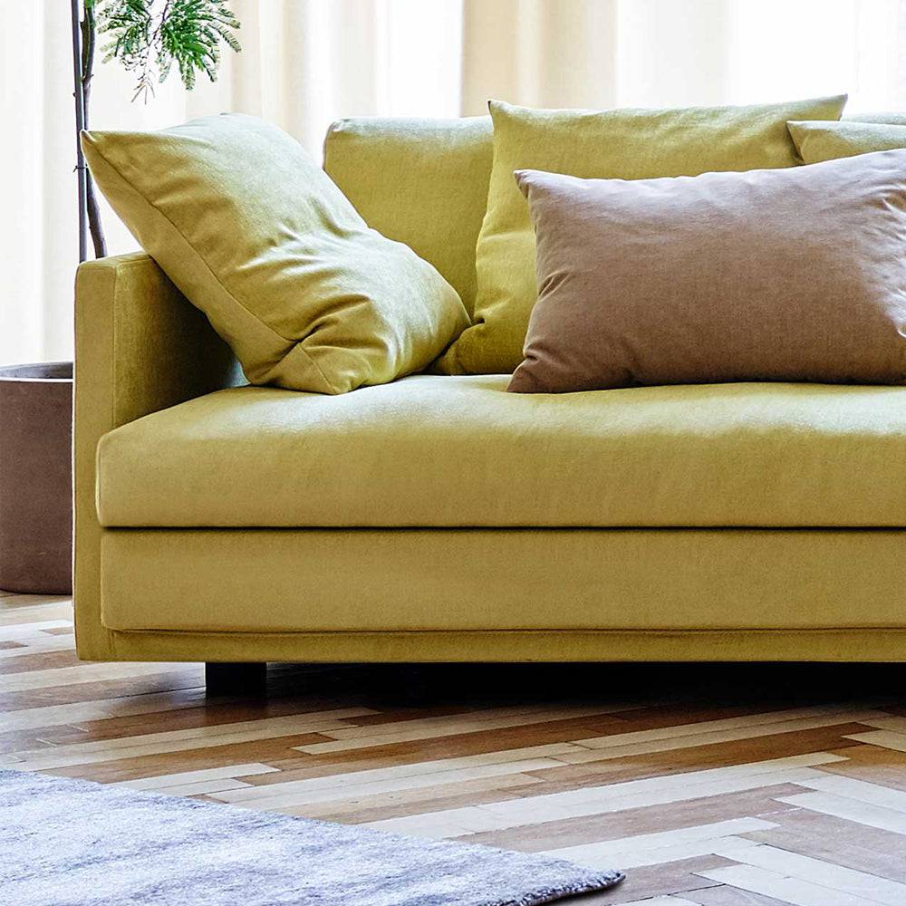 Yellow Great Ash Sofa by Eilersen with contrasting beige pillow, set on a patterned wood floor for a vibrant, modern look.
