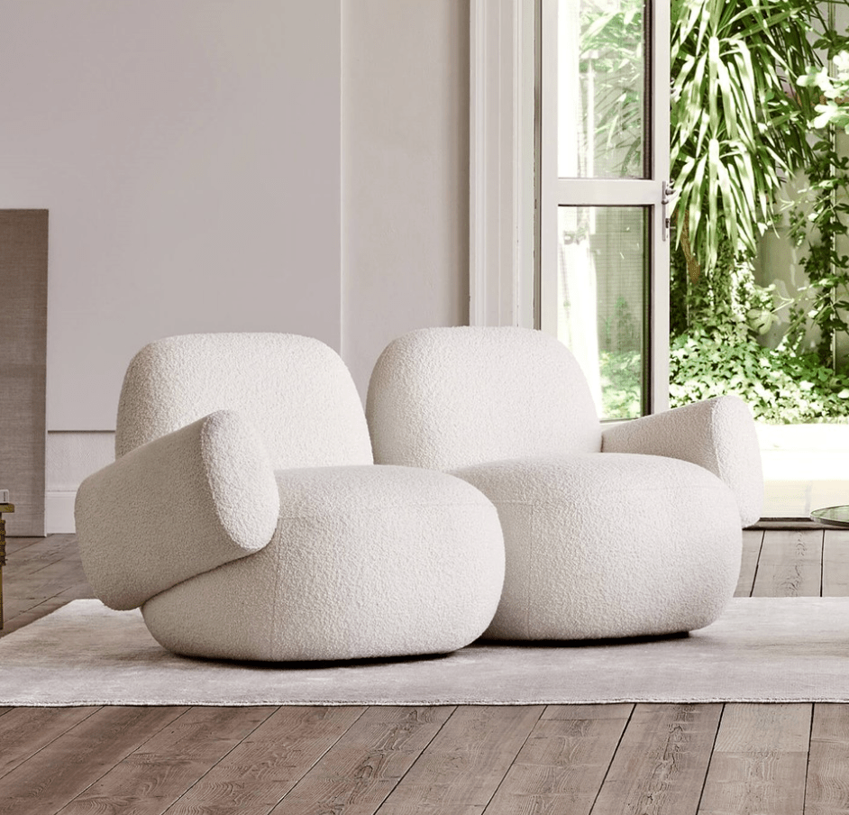 Pair of Havana Round Arm Chairs by Eilersen in white boucle, styled together on a light rug in a bright modern living space.