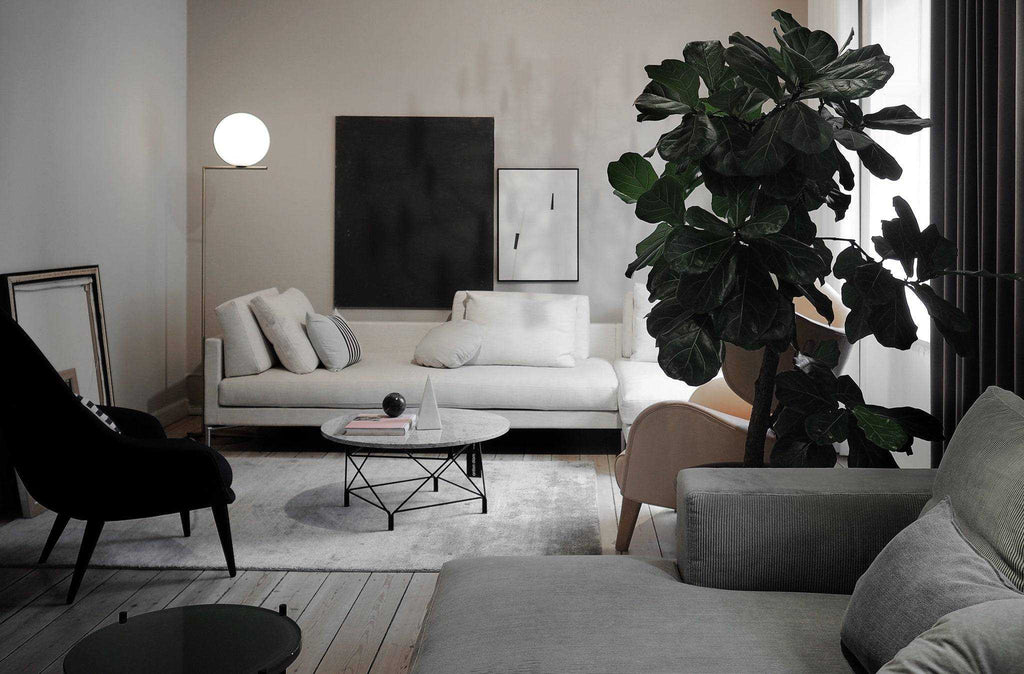 Eilersen Plano Sectional Sofa in a cozy, dimly lit room with modern art and a large indoor plant, emphasizing its versatility.