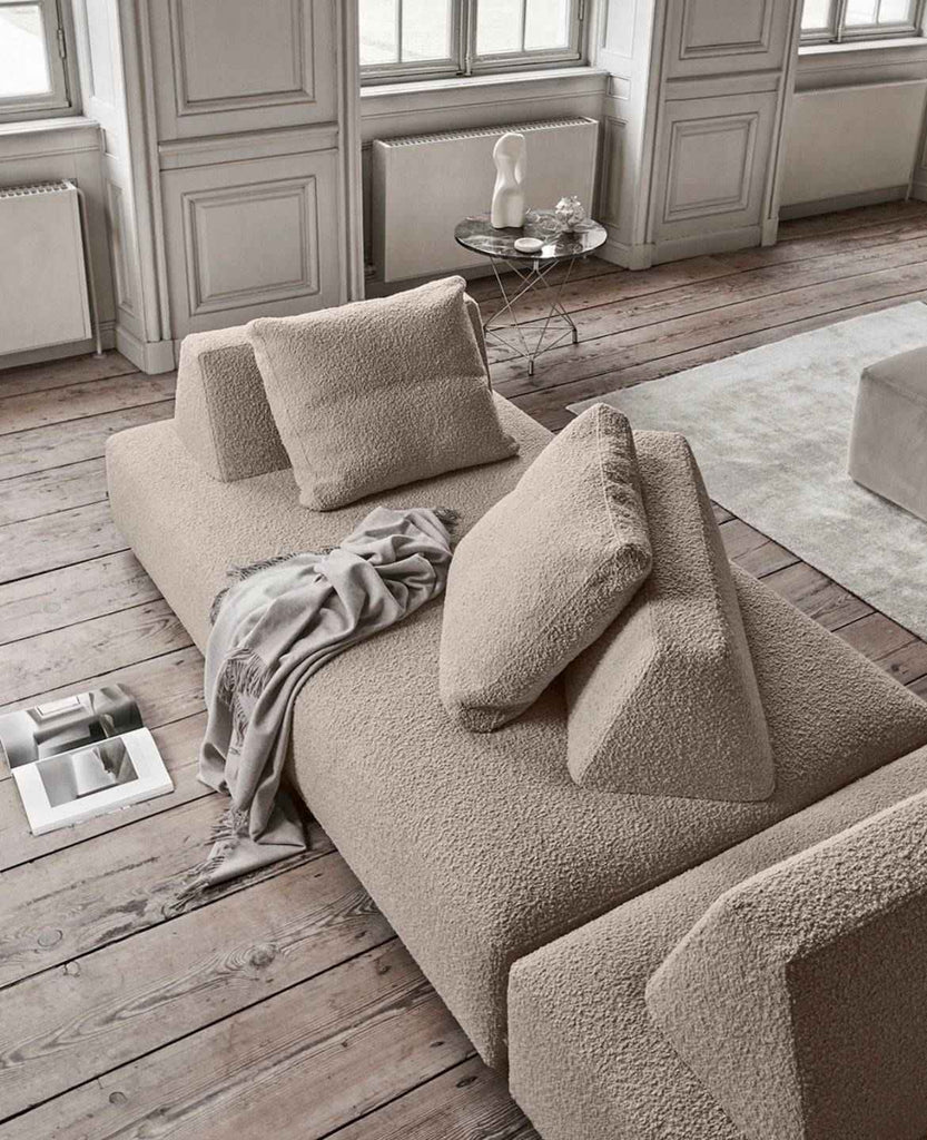 Eilersen Playground Sofa in boucle fabric with adjustable backrests, styled in a rustic room with paneled walls and wooden floors.