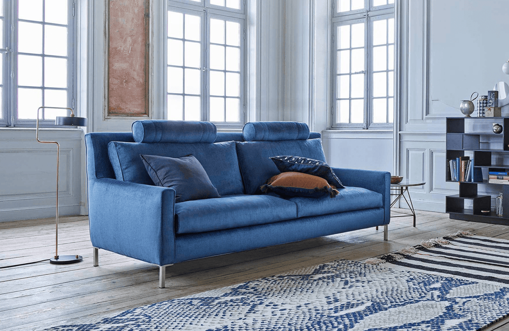 Streamline High Back Sofa by Eilersen in vibrant blue fabric, styled in a bright living room with modern decor and patterned rug.