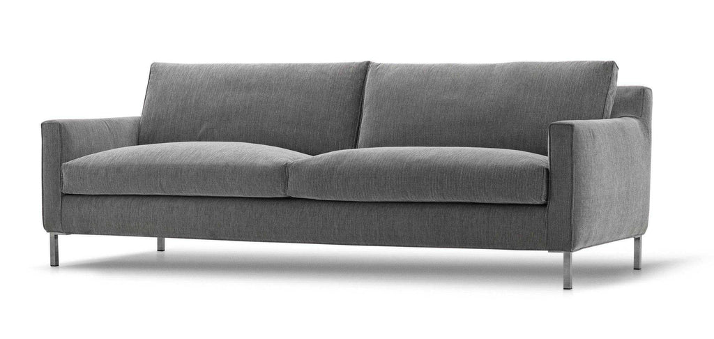 Angled view of the Streamline Sofa by Eilersen at Trade Source Furniture in grey fabric, featuring soft cushions and slim metal legs.