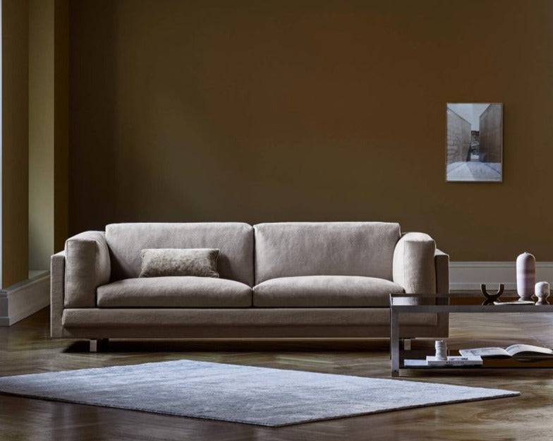Beige Eilersen Tub Sofa in a warm-toned room with a grey rug and minimalist accessories, available at Trade Source Furniture.