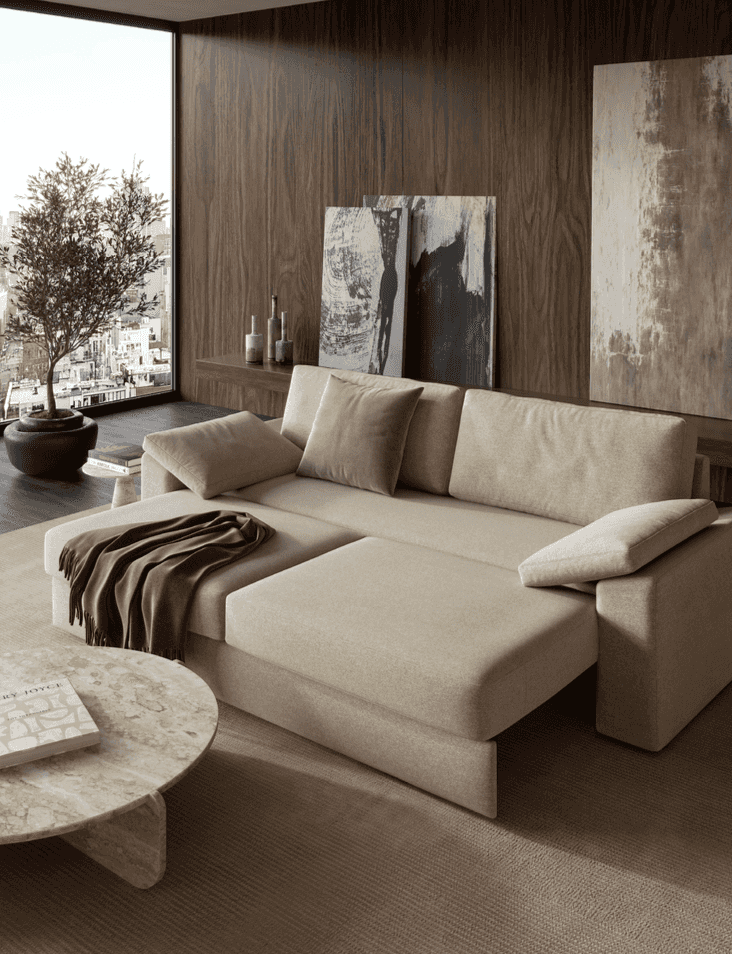 Living room with beige Vilander sofa bed featuring cushion arms, large window view, modern abstract artwork, and decorative vases