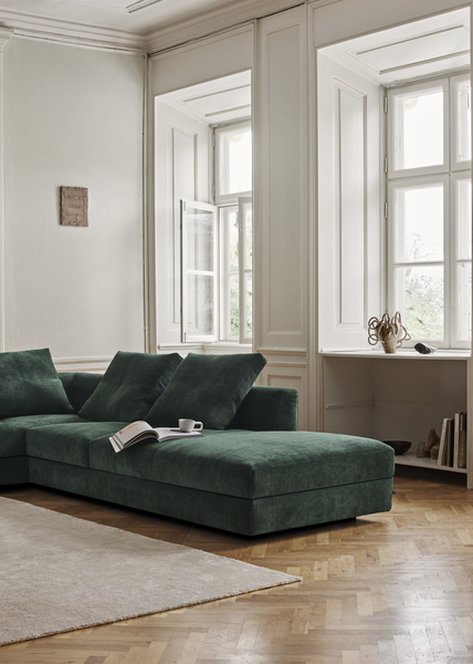 Side view of the Aton Mini Sofa by Eilersen in green, showcasing its plush cushions and soft design in a bright, elegant room. Perfect for cozy lounging.