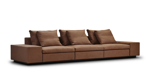 Angled view of the Dacapo Sectional Sofa by Eilersen in brown fabric, showcasing its low-profile modular design and deep seating, available at Trade Source Furniture.