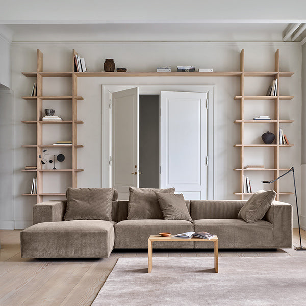Eilersen Baseline Sofa with Chaise in taupe corduroy, styled in a modern living room with open shelving and neutral decor.