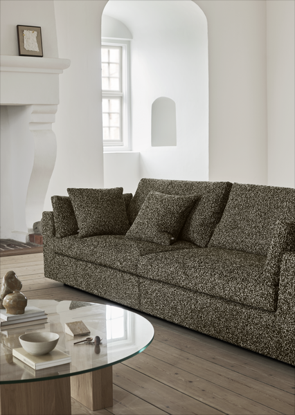 Amon Sofa by Eilersen in a textured dark fabric, styled in a minimalist living room with arched windows and wooden flooring.