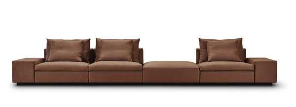 Extended configuration of the Dacapo Sofa by Eilersen with footstool bumper, in brown fabric, ideal for modern interiors, available at Trade Source Furniture.