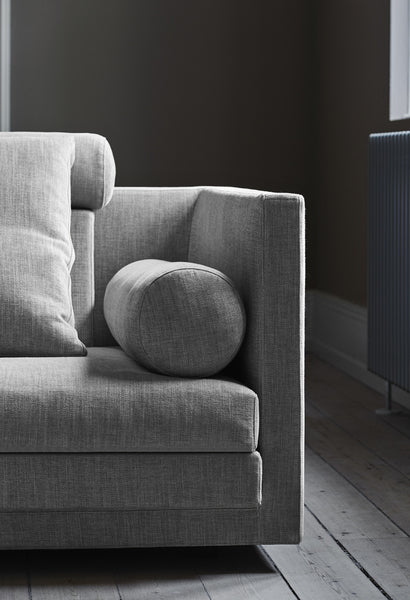 Close-up of the Cocoon Sofa by Eilersen at Trade Source Furniture in grey fabric with cylindrical bolster cushion, showcasing modern armrest design.