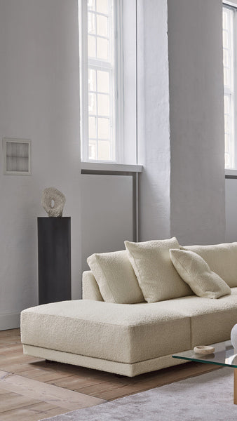 Detail view of the Drop Sofa chaise section in boucle fabric, positioned near tall windows in a minimalist interior.