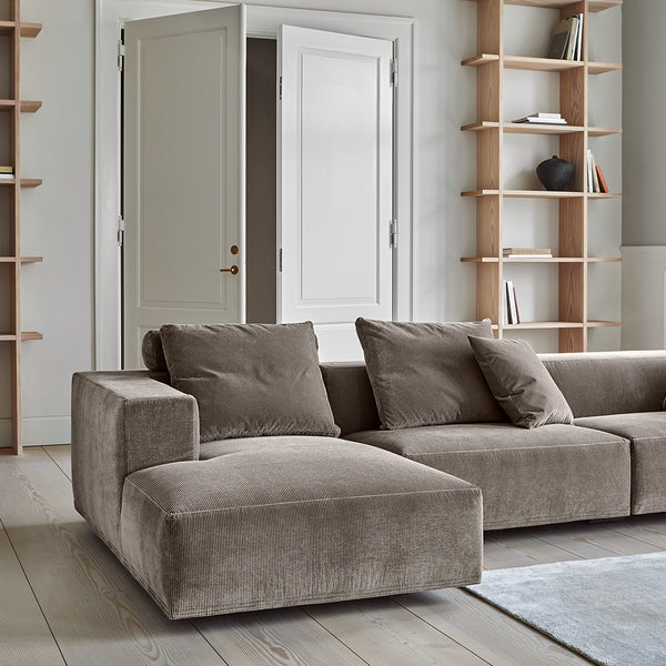 Side view of the Eilersen Baseline Sofa with Chaise in taupe, showcasing its deep seating and plush cushions in a minimalist setting.
