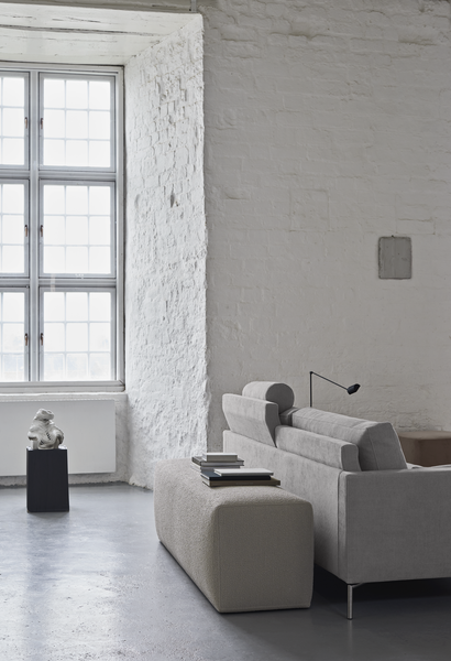 Rear view of The Great Lift Sofa by Eilersen at Trade Source Furniture, placed in a bright room with tall windows and textured walls.