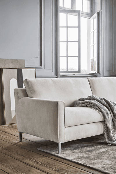 Streamline Sofa by Eilersen at Trade Source Furniture in light beige fabric, styled in a classic interior with wood flooring and open windows.