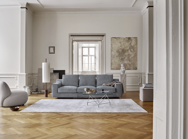 Aton Mini Sofa by Eilersen in light blue fabric centered in a spacious, elegant room with minimalist decor. Compact luxury for modern living spaces.