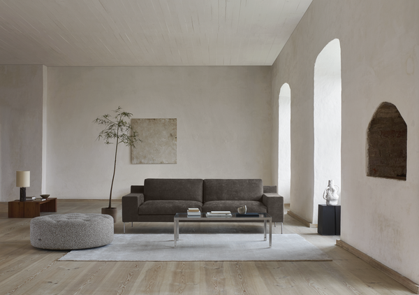 Shu Sofa by Eilersen in dark grey fabric placed in a minimalist room with neutral tones, emphasizing its sleek and timeless design.