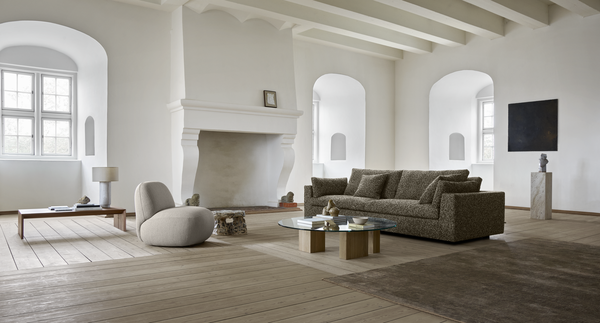 Modern living room featuring the Amon Sofa by Eilersen, paired with a glass coffee table and soft lighting for a cozy ambiance.