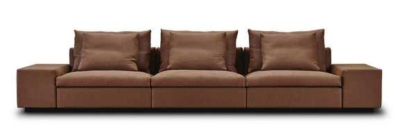 Front view of the Dacapo Sofa by Eilersen in brown upholstery, featuring three center sections and plush back cushions, part of the Trade Source Furniture collection.