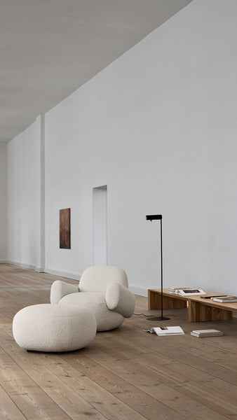 Bright interior with Havana Lounge Chair by Eilersen in beige boucle, styled beside a glass coffee table and neutral rug.