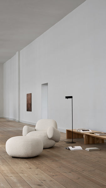 Bright interior with Havana Lounge Chair by Eilersen in beige boucle, styled beside a glass coffee table and neutral rug.