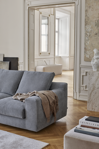 Close-up of striped Aton Mini Sofa by Eilersen with throw blanket, placed in a classic room with elegant trim. Blends comfort with sophisticated design.